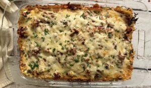 cheesy lasagna topped with fresh chopped parsley in a 9x13 glass baking dish.