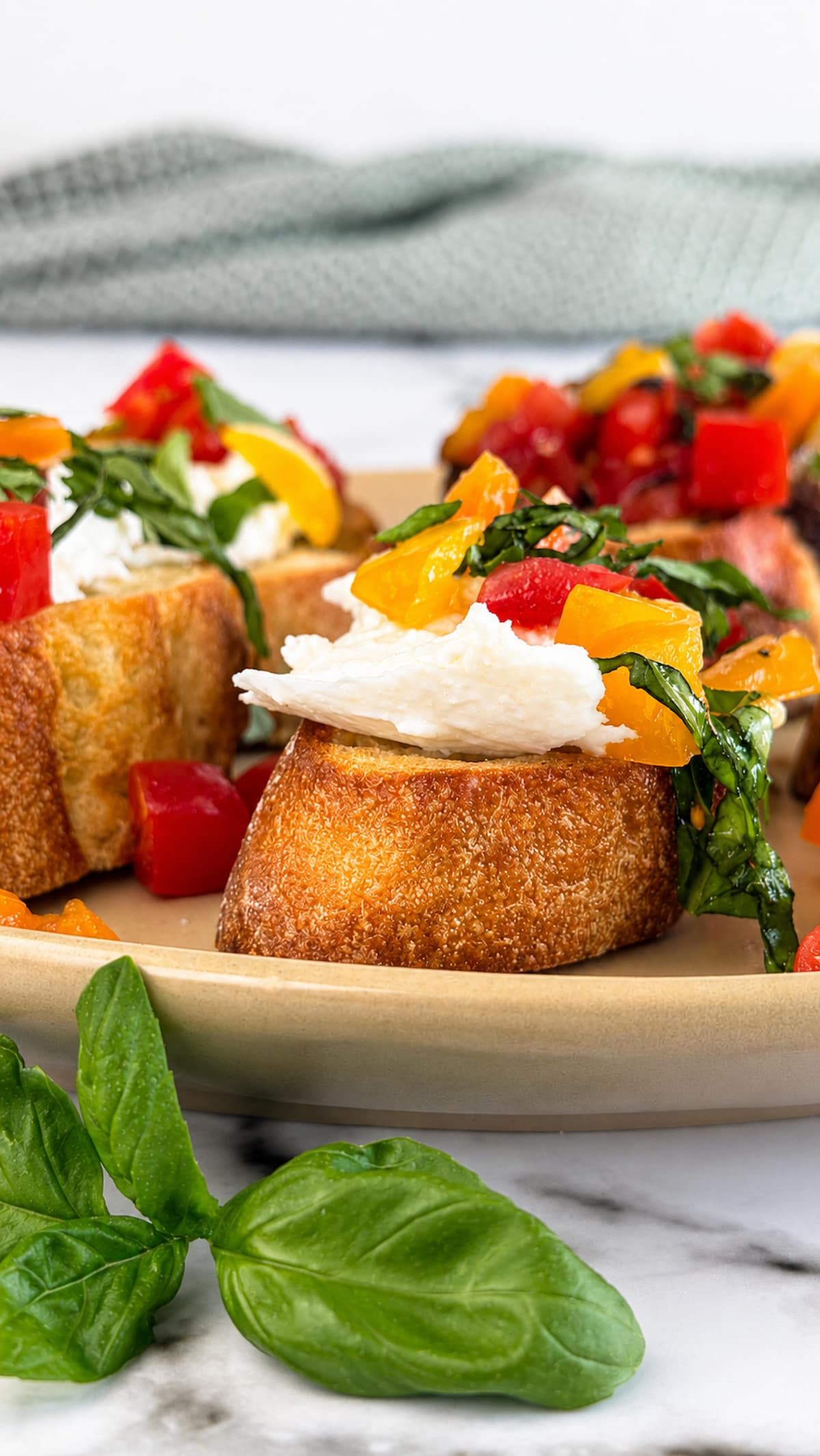 Burrata bruschetta made with creamy burrata cheese, marinated red and yellow cherry tomatoes, and fresh basil on toasted artisan bread, arranged on a serving platter.