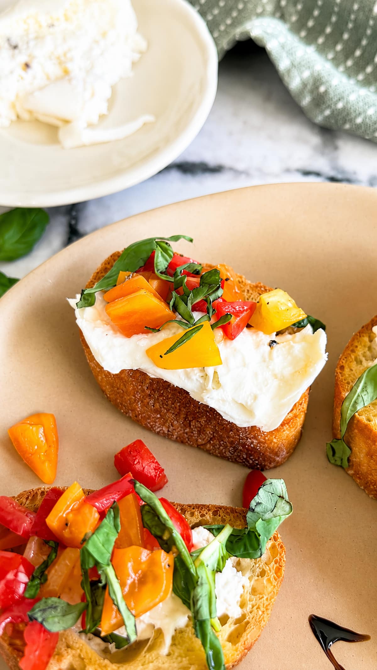 Burrata bruschetta made with creamy burrata cheese, marinated red and yellow cherry tomatoes, and fresh basil on crispy toasted bread, served on a platter.