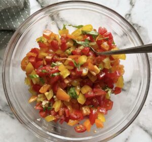 bowl of chopped multi-coloured cherry tomatoes with fresh basil, garlic, and olive oil. spoon in the bowl.