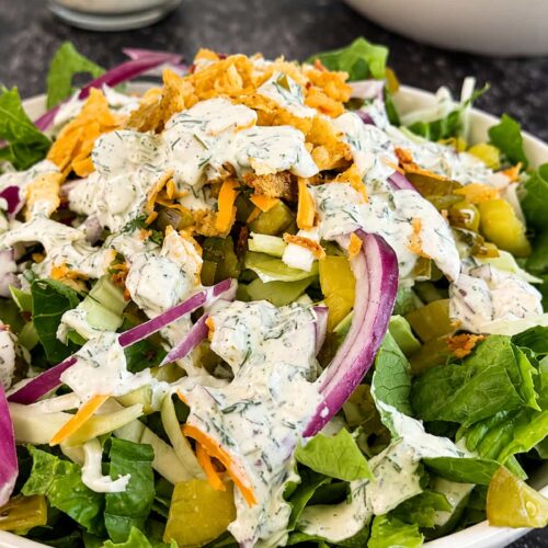 Chopped dill pickle salad with crisp romaine, pickles, red onion, cheddar cheese, and creamy dill dressing.