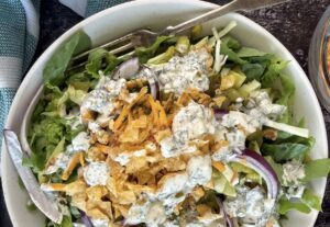 Chopped dill pickle salad with romaine lettuce, cheddar cheese, red onion, dill pickles, crispy onions, fresh dill and drizzled with a creamy pickle ranch dressing.