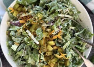 Chopped dill pickle salad with romaine lettuce, cheddar cheese, red onion, dill pickles, crispy onions, and fresh dill in a bowl with two forks.