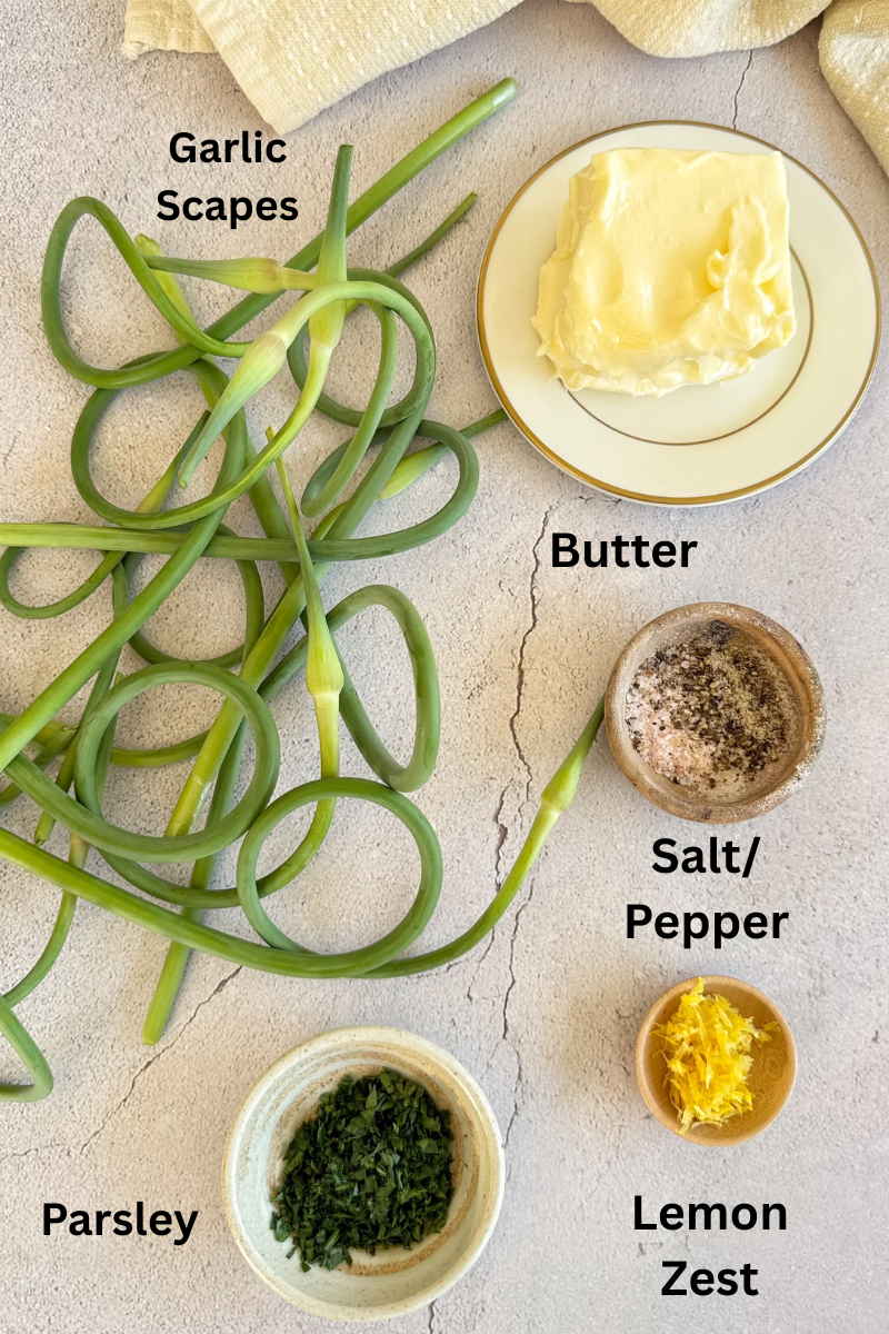 ingredients to make homemade garlic scape butter - fresh garlic scapes, butter, salt, pepper, lemon zest, and parsley.