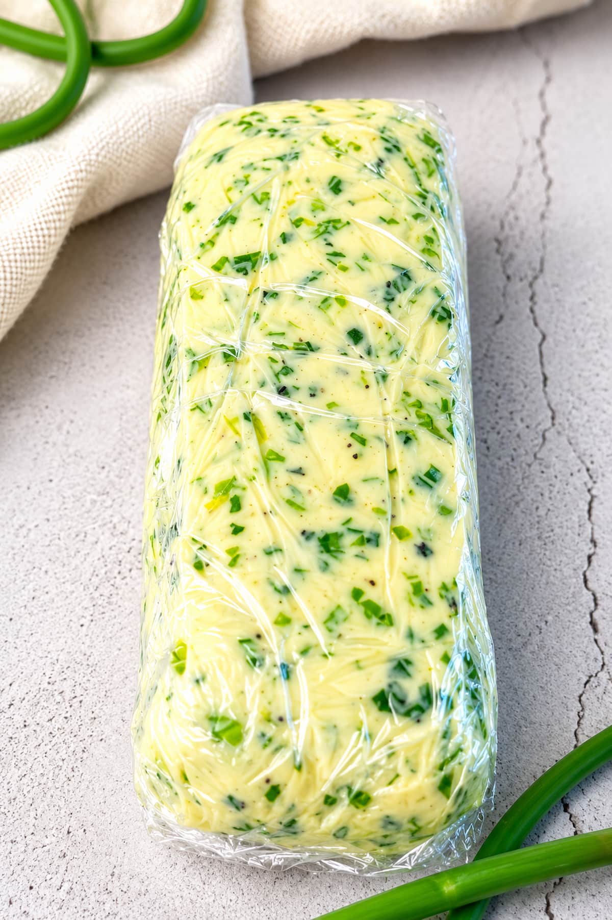 Garlic scape butter wrapped in plastic wrap, ready for chilling or freezing.