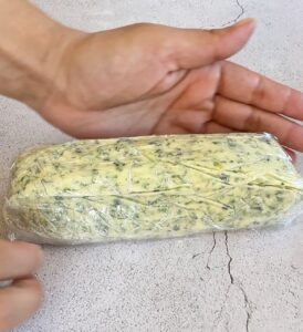 Garlic scape butter wrapped in plastic wrap, ready for chilling or freezing.