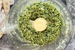 pulsed garlic capes, parmesan, and spices in the base of a food processor making homemade garlic scape pesto.