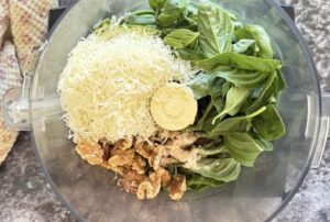 freshly grated parmesan cheese, walnuts, fresh basil leaves, and garlic scapes in the base of a food processor.