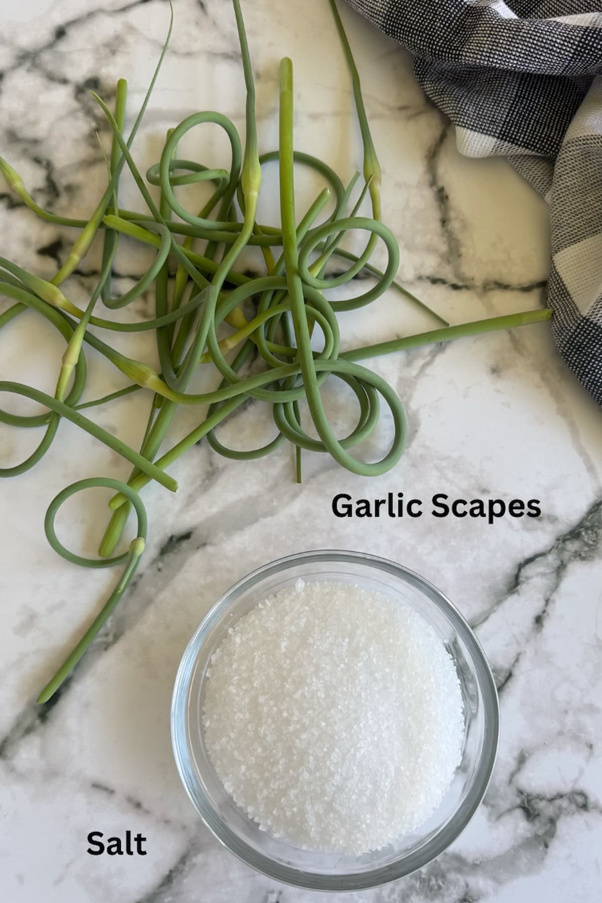 ingredients for homemade garlic scape salt - garlic scapes and coarse salt in a bowl.