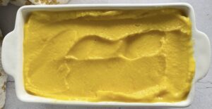 mango orange sorbet spread out into a glass white loaf pan.