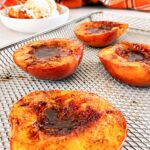 Air fryer peach halves caramelized with cinnamon and brown sugar on an air fryer basket.