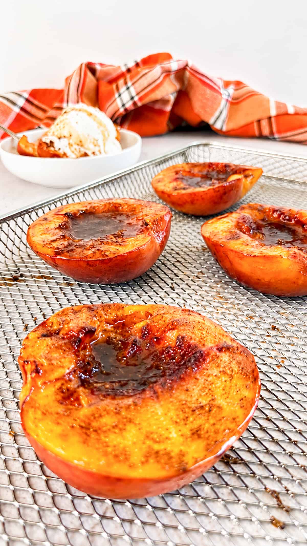 Air fryer peach halves caramelized with cinnamon and brown sugar on an air fryer basket.