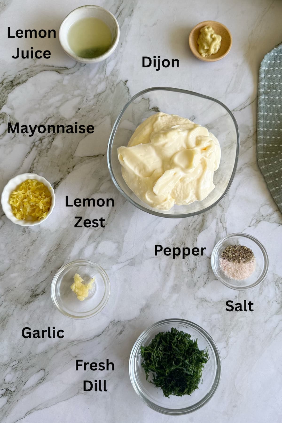 ingredients for dill mayonnaise in separate bowls - lemon juice, dijon, mayonnaise, lemon zest, pepper, salt, fresh dill, and garlic.