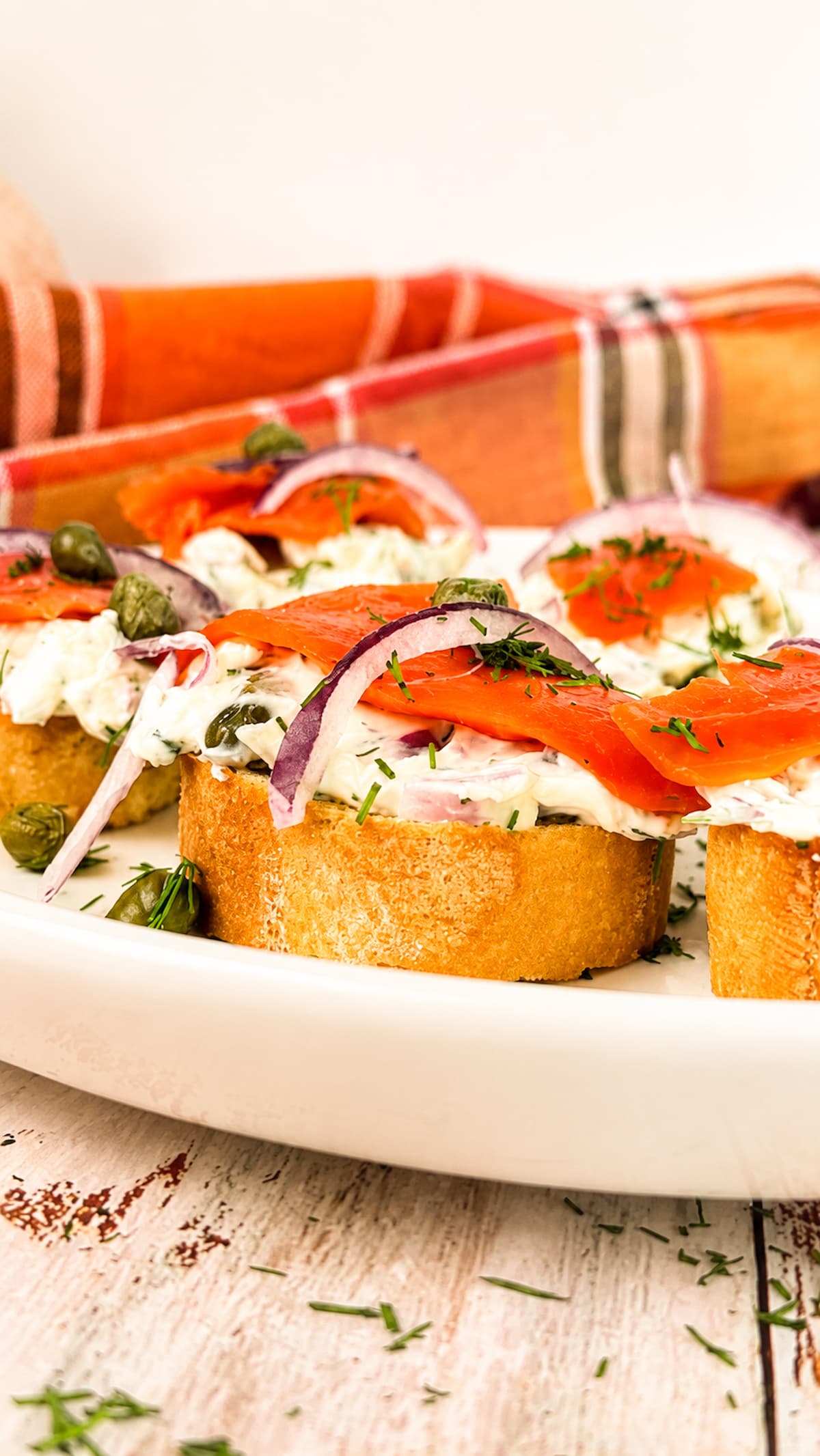 Smoked salmon crostini with creamy dill spread, red onion, capers, and fresh dill on toasted baguette slices.