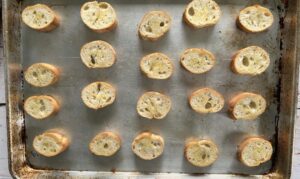 toasted baguette slices on a baking sheet.