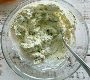 herb and garlic cream cheese mixture in a glass bowl with a fork.