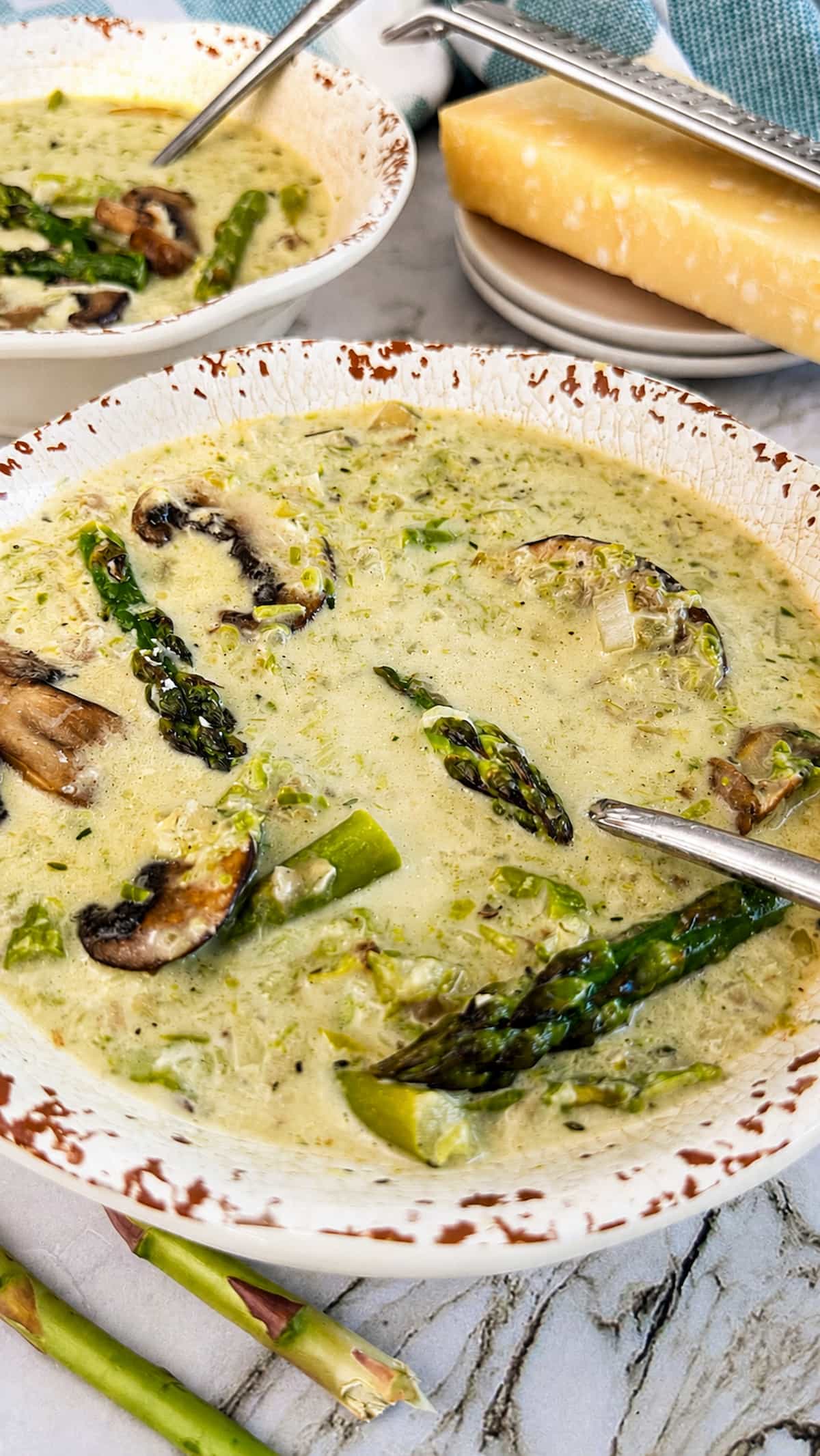 Creamy mushroom and asparagus soup with tender asparagus, sliced mushrooms, and herbs in a rustic bowl.