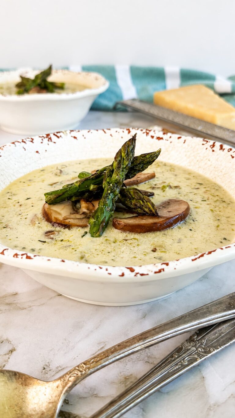 Creamy mushroom and asparagus soup topped with sautéed mushrooms and roasted asparagus in a rustic white bowl.
