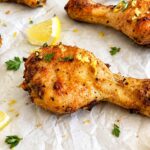 Lemon pepper chicken drumsticks with fresh thyme, lemon zest, and lemon wedges.