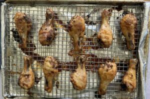 cooked lemon pepper chicken drumsticks on a wire rack lined baking sheet.