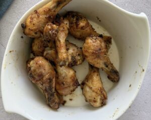 cooked lemon pepper chicken drumsticks in a white bowl.
