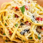 Linguine pasta salad with colorful vegetables, black olives, fresh herbs, and grated Parmesan cheese.
