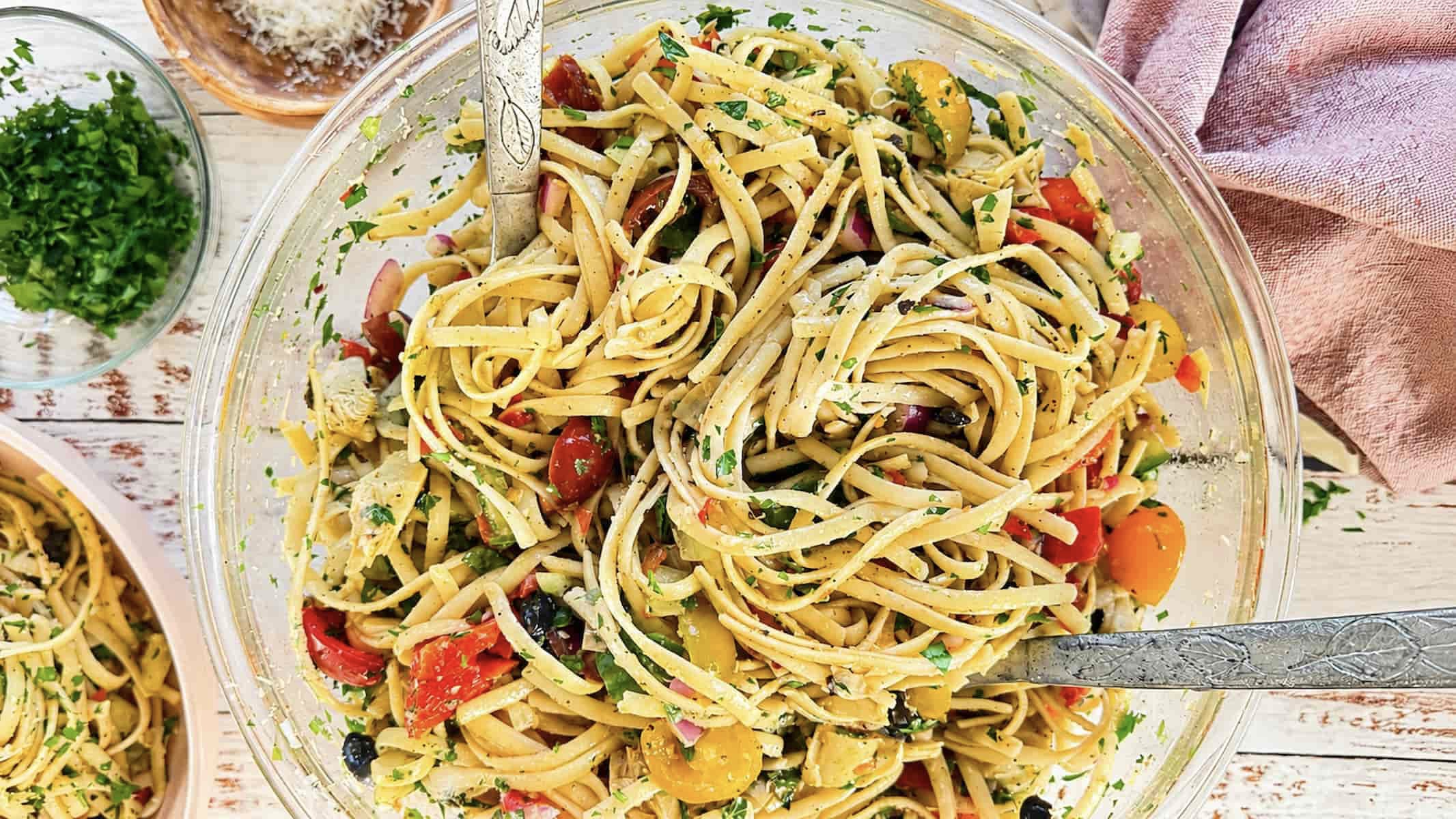 Linguine pasta salad with cherry tomatoes, artichokes, black olives, red onion, fresh parsley, and Parmesan cheese.