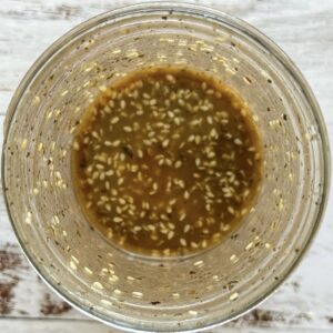 brown homemade salad dressing with sesame seeds in a jar.