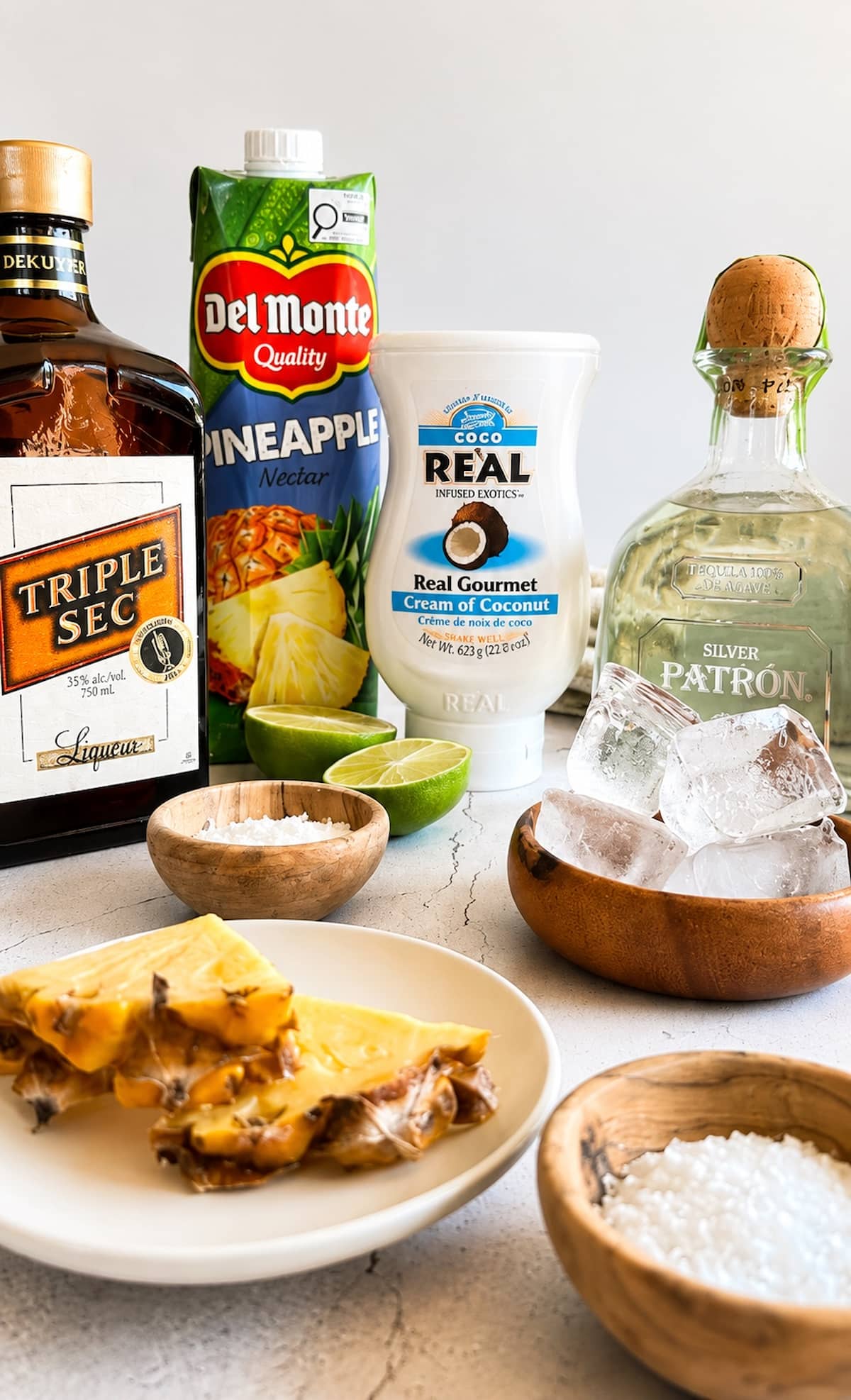 Pineapple coconut margarita ingredients with tequila, triple sec, pineapple nectar, cream of coconut, fresh pineapple, lime, salt, and ice.