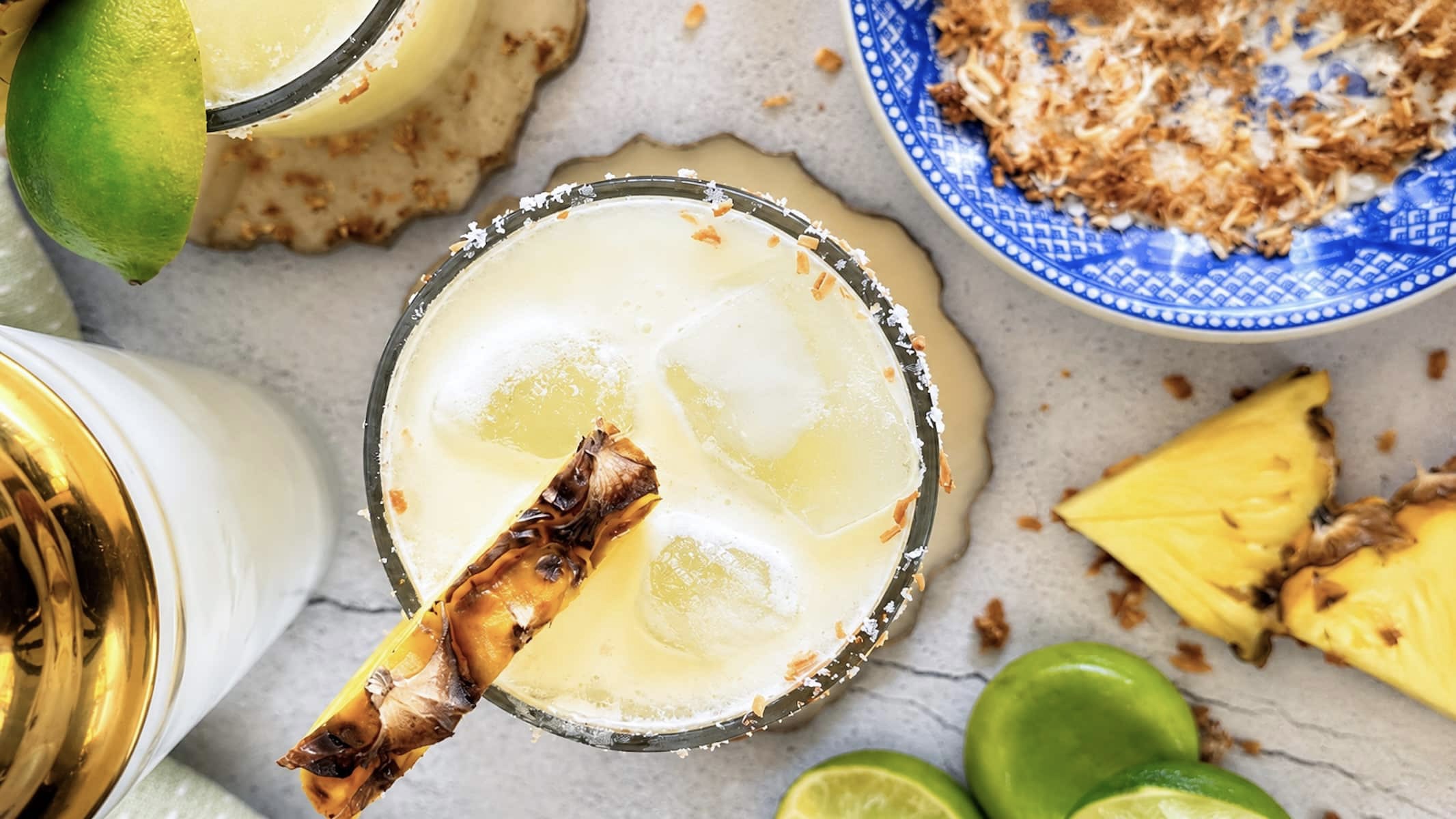 Pineapple coconut margarita with ice, fresh pineapple, lime, and a toasted coconut salt rim.