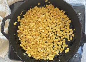 corn kernels cooking in a cast iron skillet.
