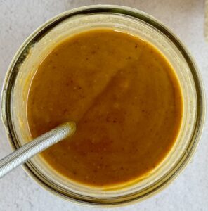 creamy peanut butter dressing in a jar with a little whisk.