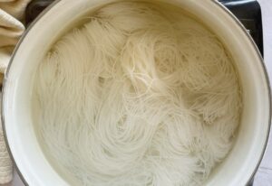 thin rice noodles in water in a pot.