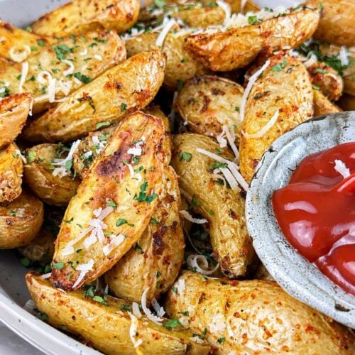 Crispy air fryer fingerling potatoes topped with Parmesan and fresh parsley, served with ketchup for dipping.