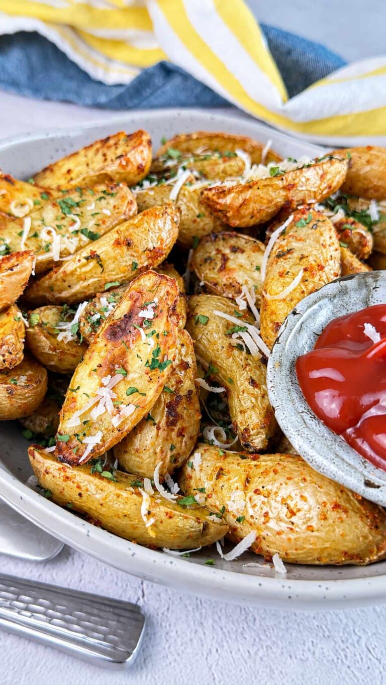 Crispy air fryer fingerling potatoes topped with Parmesan and fresh parsley, served with ketchup for dipping.
