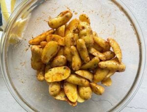 halved seasoned uncooked fingerling potatoes in a glass bowl.