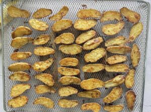 halved seasoned air fryer fingerling potatoes cut side up in an air fryer tray.