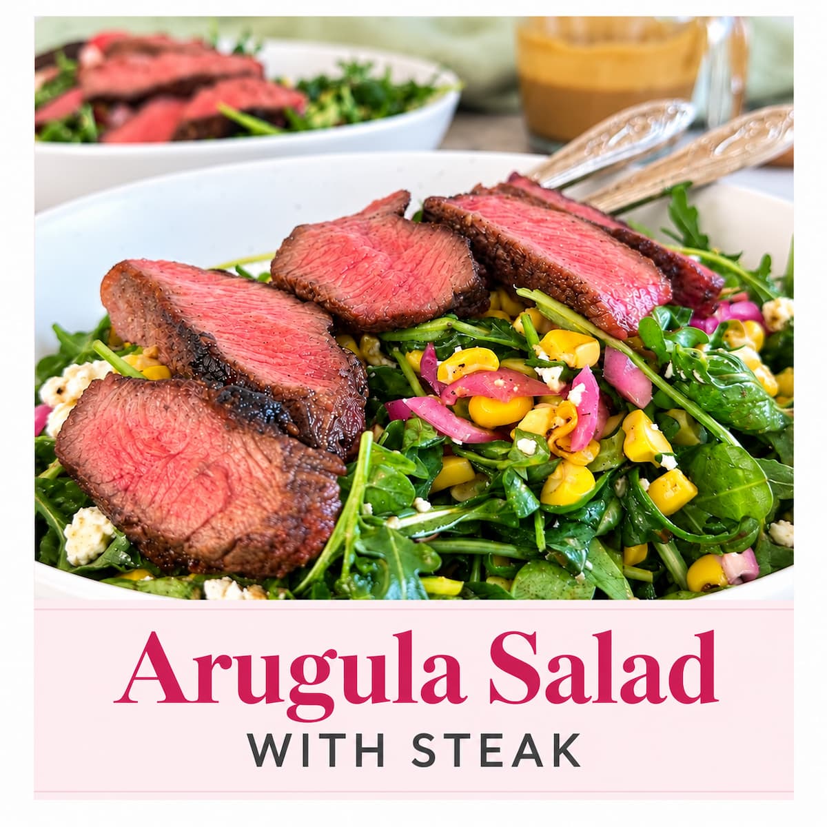 Arugula salad with sliced steak, charred corn, feta, and pickled red onions, with a nectarine balsamic dressing in the background.