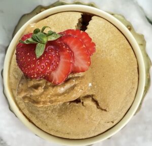 freshly baked oats without banana in a ramekin topped with peanut butter and sliced strawberries.