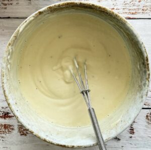 creamy mayo dressing for crispy potato salad in a bowl with a whisk.