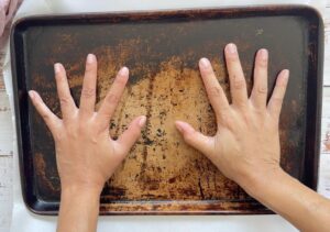 two hands pressing a baking sheet down.