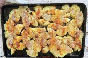 smashed potatoes drizzled with olive oil and spices on a baking sheet.