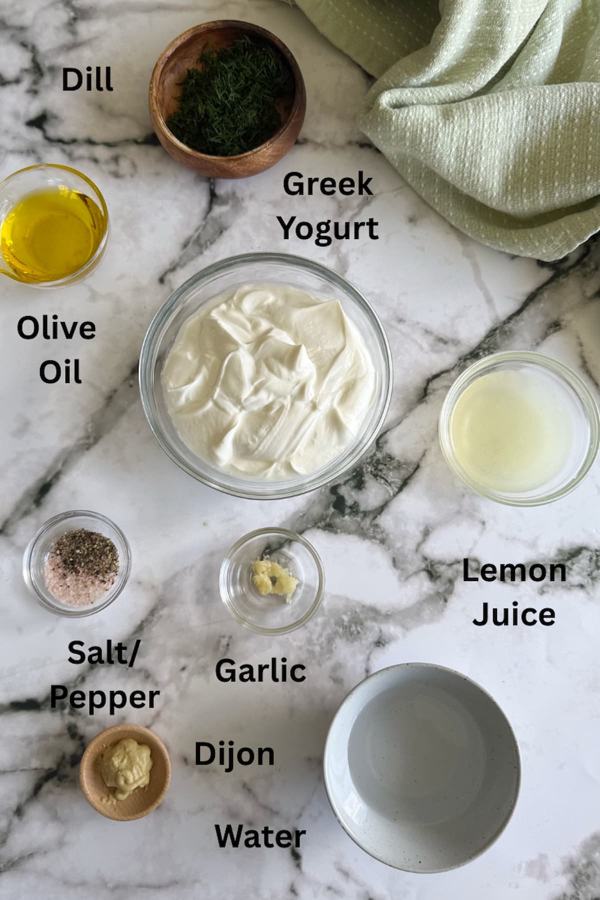 ingredients to make dill dressing laid out in separate bowls - greek yogurt, dill, olive oil, salt/pepper, dijon, water, garlic, and lemon juice.