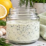 Creamy dill yogurt salad dressing with fresh dill, lemon, and garlic in a glass jar.