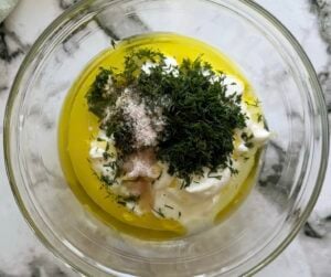 ingredients to make dill dressing unmixed in a large glass bowl.