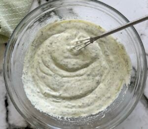 creamy dill yogurt dressing in a glass bowl with a little whisk.