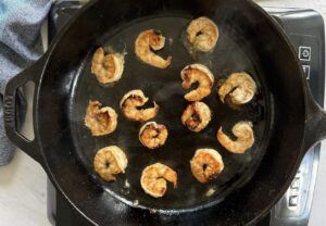 jerk marinated shrimp cooking in a black cast iron skillet.