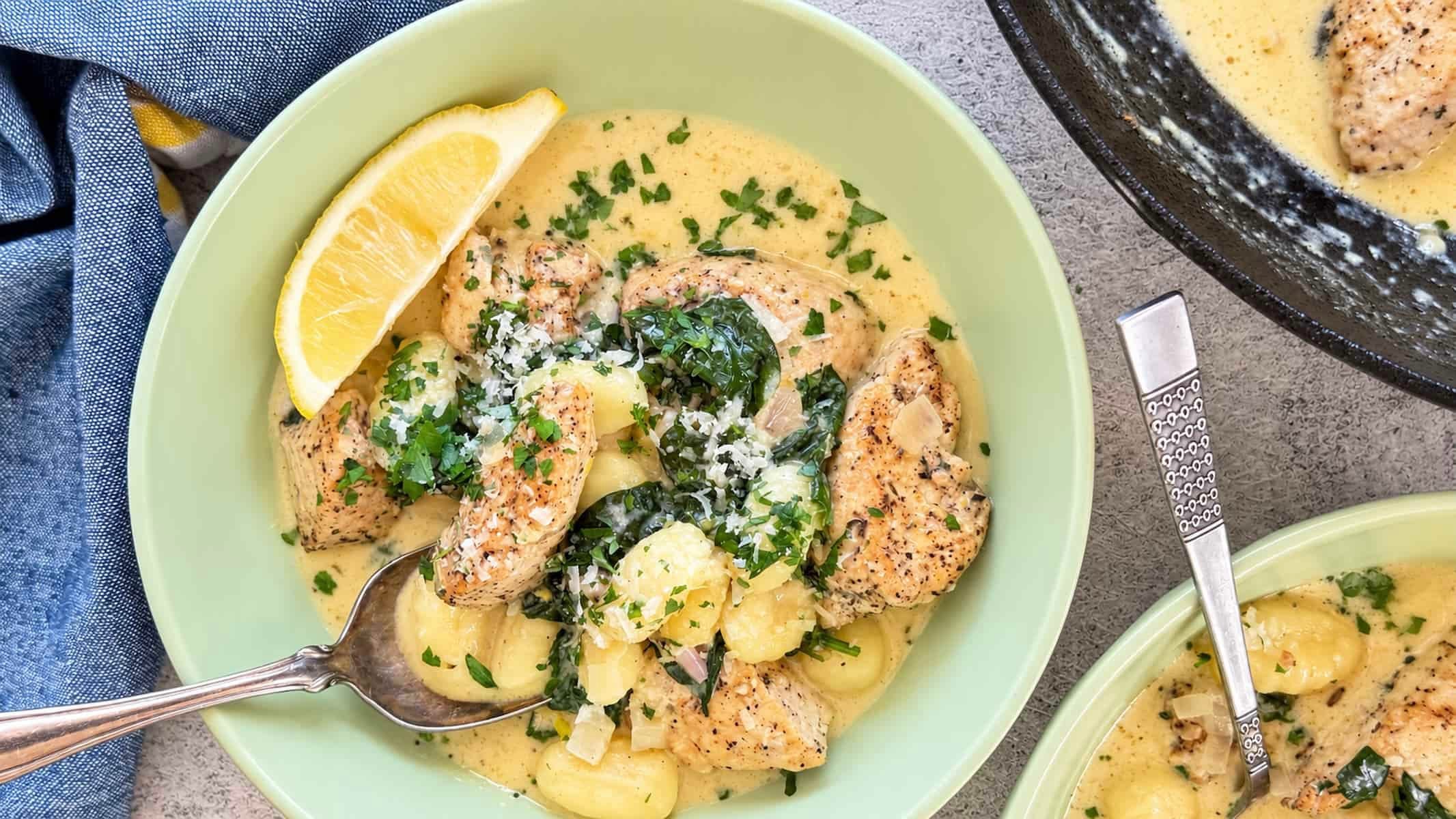 Creamy lemon chicken gnocchi with spinach, Parmesan, fresh parsley, and a lemon wedge.