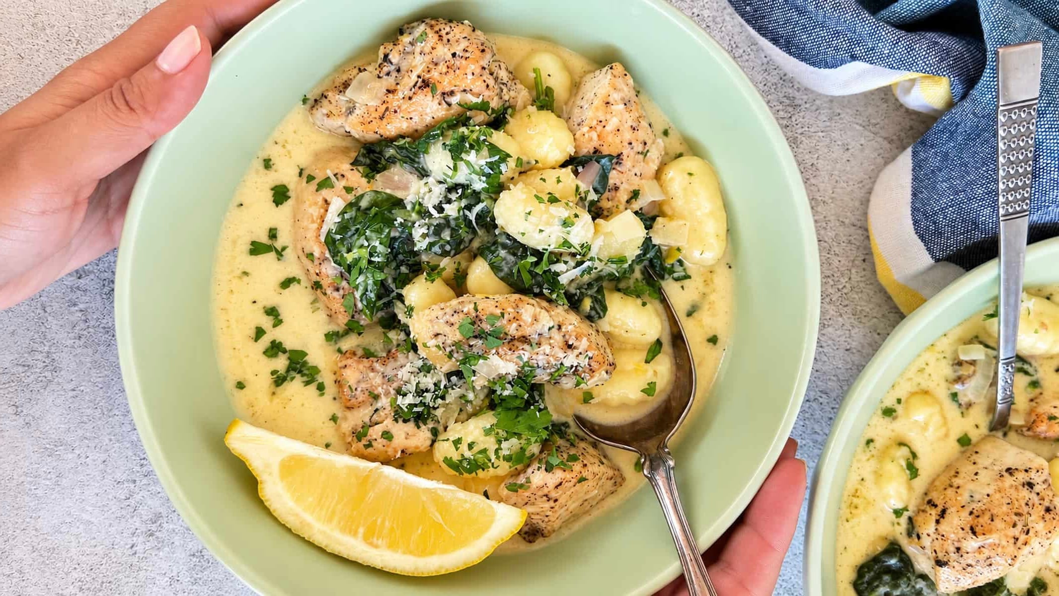 Creamy lemon chicken gnocchi with spinach, Parmesan, fresh parsley, and a lemon wedge.