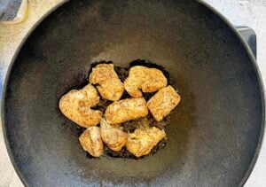 cooked seasoned chicken breast chunks in a large cast iron wok.
